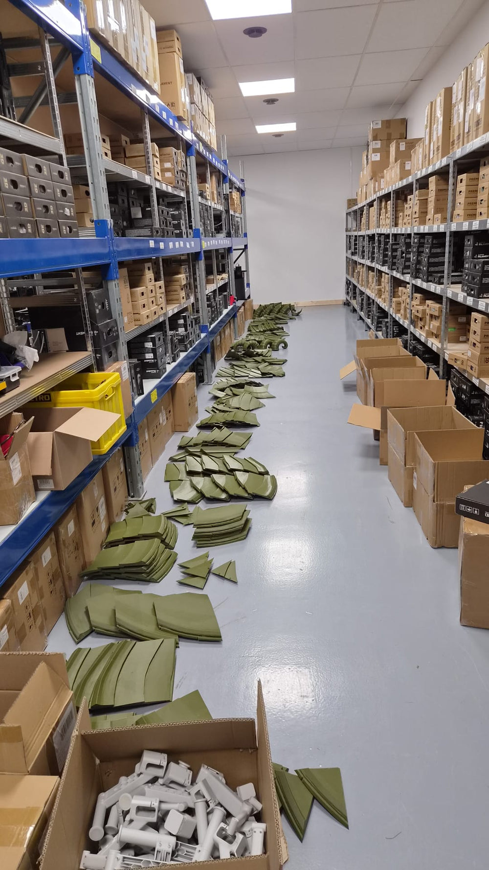 Viele grüne Dachsegmente in Gruppen auf dem Boden zwischen Lagerregalen